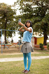 Obraz premium Smiling Young woman having a video call on smartphone outdoors in a park