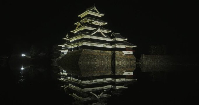 Glowing, beautiful 16th century Matsumoto castle reflecting in pond at night