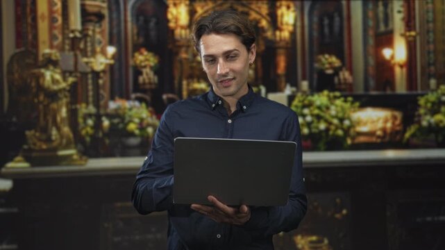 Man holding laptop makes ok sign around eye in ornate building altar setting with candles and statues; confidence focus.