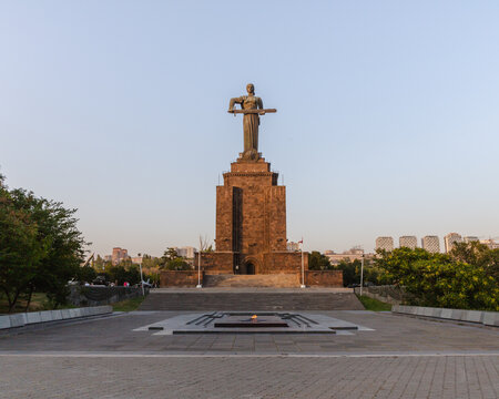 View of the monumental Mother Armenia statue standing tall atop a stone pedestal, with an eternal flame burning brightly in front, Yerevan, Yerevan, Armenia.