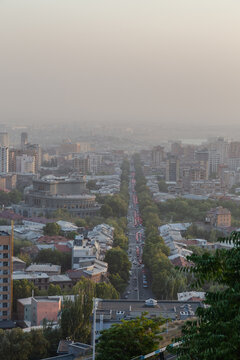 View of a dusty haze settling over the city, muting the colors of buildings and trees along a central avenue bustling with traffic, Yerevan, Yerevan, Armenia.