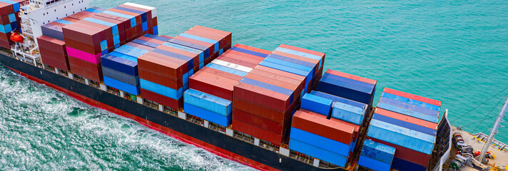 cargo ship, fully loaded with containers, sailed out of the port into the sea.