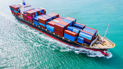 cargo ship, fully loaded with containers, sailed out of the port into the sea.