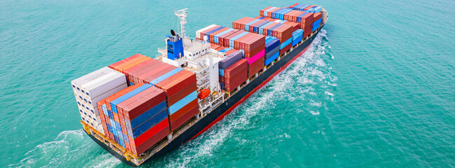 cargo ship, fully loaded with containers, sailed out of the port into the sea.