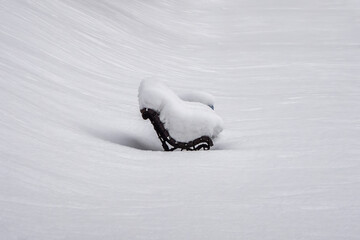 A bench covered in snow sits in the snow