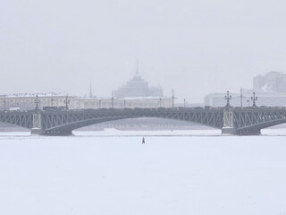 Minimalistic winter view with a small figure of a man on a frozen and snowy river