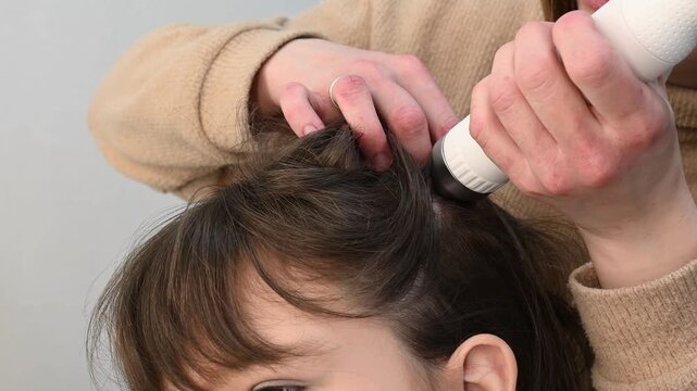 Trichologist examines hair and scalp of young woman in salon using trichoscope and dermatoscope. Woman's hair loss, dandruff and oily hair problems, scalp treatment and hair care consultations
