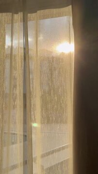 Warm golden hour sunlight shining through sheer white curtains. Home interior lifestyle. Natural light in interior design. Calm, minimal living. Evening mood.