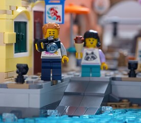 Fototapeta premium Tambov, Russian Federation - January 05, 2026 Lego man minifigure with camera and a girl with ice cream standing on a dock.