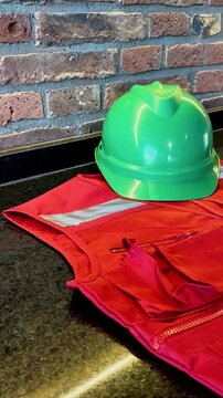 Panning shot of red safety vest and green helmet resting on stone table at construction site
