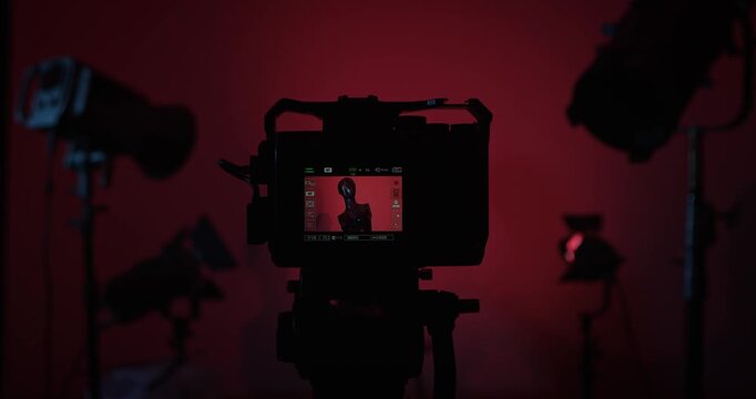 The operator turns on the camera and adjusts the lighting in the photo studio with lighting equipment. A mannequin is displayed on the camera screen. Backstage photo shoot .