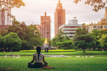 woman practice meditation in green city park, conscious female meditating in nature, mental health and mindfulness urban concept, balance and harmony in modern environment