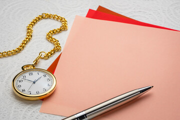 classic pocket watch with a chain and a stack of blank notes with a pen