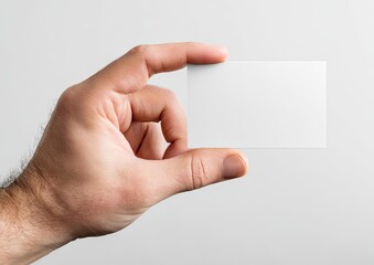 Obraz premium A hand holding a blank rectangular card, angled slightly, against a white background