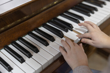 Child's Hands Playing Piano Keys on a Vintage Wooden Musical Instrument