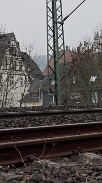 Village Scenery With Train Rails. Tracks In Countryside Amidst Overcast Weather. Photograph Showcasing Train Tracks Traversing Village Area With Overcast Skies And Industrial Surroundings