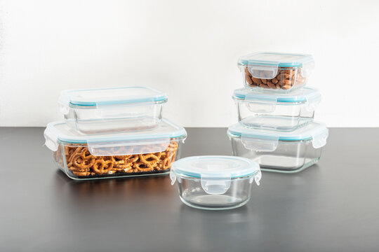 clear plastic containers with food and a transparent glass lids resting side-by-side on a white tabletop