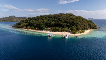 Naklejka premium Drone Aerial view of Banana Island, a tropical beach with turquoise water, white sand, and a bangka boat in Coron, Palawan, Philippines