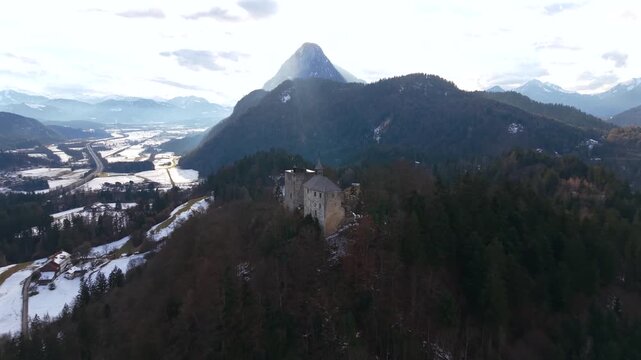 Cinematic drone video of Thierberg Castle ruins above Kufstein, Austria. Popular alpine viewpoint showing the Inn River, Inntal, snowy hills and the Kaiser Mountains in winter landscape.