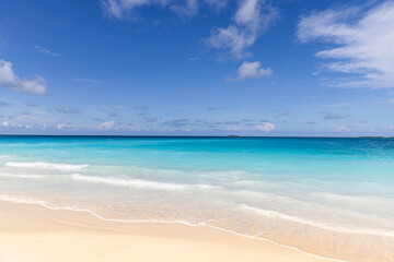 Obraz premium Sunny beach blue ocean sunshine fluffy clouds clear sky. Summer nature landscape vacation inspiration shore seaside tropical island coast paradise turquoise water serene scenery bright day wallpaper