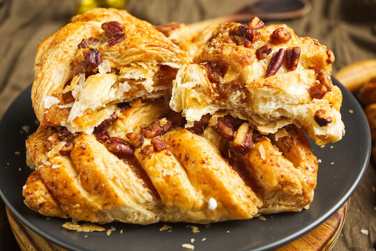 Pecan braid. A puff pastry roll, often Danish-style, filled with a creamy mixture of pecans and sugar. Black background.