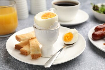 Tasty breakfast with hard boiled egg served on grey table, closeup