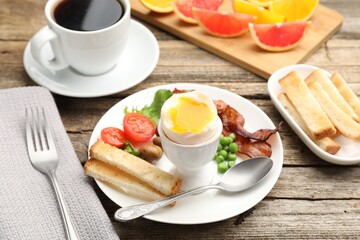 Tasty breakfast with soft boiled egg and bacon served on wooden table, closeup