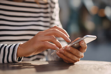 Close up of a persons hands using a smartphone.