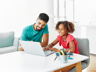 Obraz premium Father and daughter doing homework with laptop at home. Father and teenage girl happy using laptop. Teen girl and dad sitting at home working with notebook