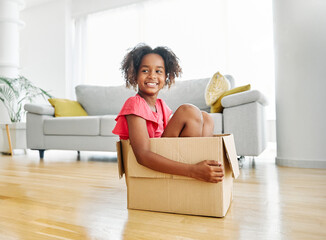 mother pushing his daughter sitting in a cardboard box, having fun at home