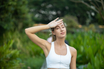 Obraz premium A woman wipes her forehead while enjoying the warmth of the sun in a beautiful outdoor setting.