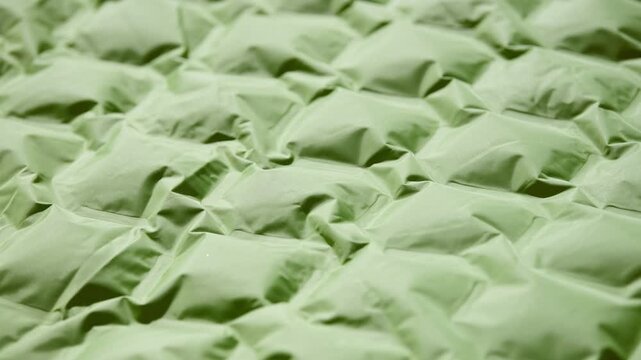 Inflatable mattress gradually filling with air close-up green material soft texture