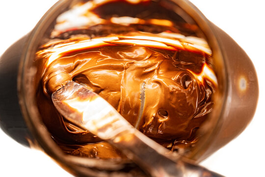Closeup of the inside of a nearly empty jar of hazelnut spread with a silver butter knife inside