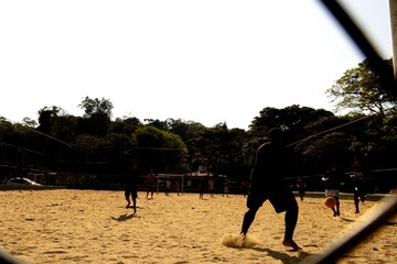 Meninos jogando futebol em campo de terra no pôr do sol.  © Luiz Leite