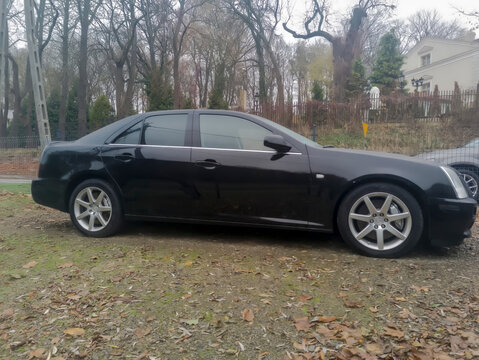 Polska, Ostrowiec Świętokrzyski, 10 listopada 2025, 12:22. CADILLAC V8 NORTHSTAR na parkingu jesienią. Samoch&oacute;d ma elegancką sylwetkę sedana ze srebrnymi felgami aluminiowymi. Wok&oacute;ł niego rosną drzewa