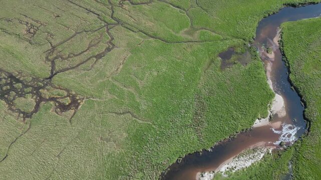 survol des m&eacute;andres et ramifications d'une rivi&egrave;re dans une prairie 