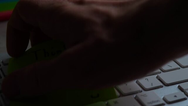 "Think Bigger" green sticky note left on keyboard. The bright note stands out against the keys, symbolising motivation, productivity, and a focused mindset. Shot in 4K, slow-motion, 50FPS.