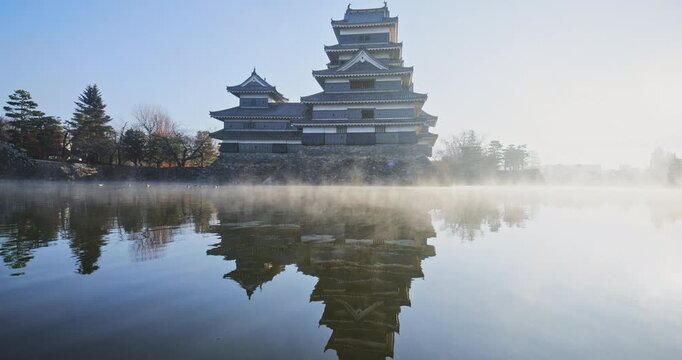 Mist on surface of pond near beautiful 16th century Matsumoto castle at sunrise