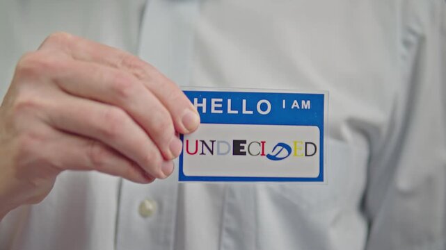 undecided badge on shirt.Individual adjusts sticker on professional attire with uncertainty
