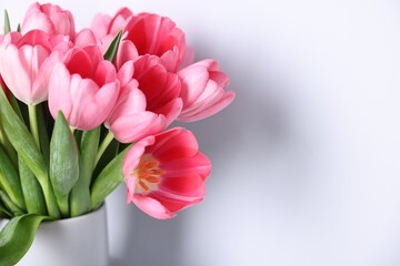 Bouquet of pink tulips in vase on light grey background, closeup. Space for text