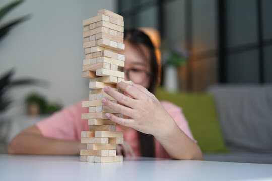 Young female playing wooden tower blocks board game at home.