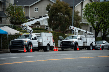 Utility bucket trucks parked on residential street with safety cones and temporary tent © Tom Harwood
