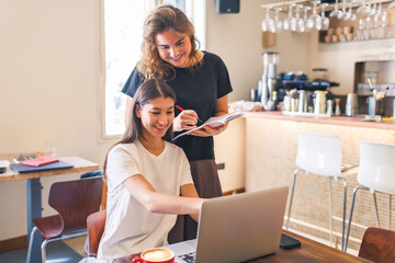 Two friends enjoying a productive moment while working on laptops in a cozy cafe together