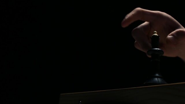 Close-up of a chess player's hands as they checkmate their opponent. Chess game on a black background, with the queen eating the king