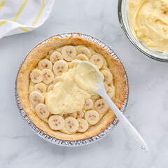 Above view of vanilla pudding custard being spread onto a banana cream pie.