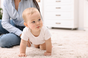 Fototapeta premium Mother with her cute little baby on floor at home, closeup. Space for text