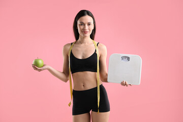Obraz premium Woman with scales, green apple and measuring tape on pink background