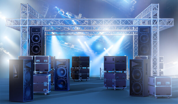 Event production, Concert staging. Professional audio speakers, lighting truss, and equipment cases arranged on stage, prepared for live performance, show setup, or entertainment event.