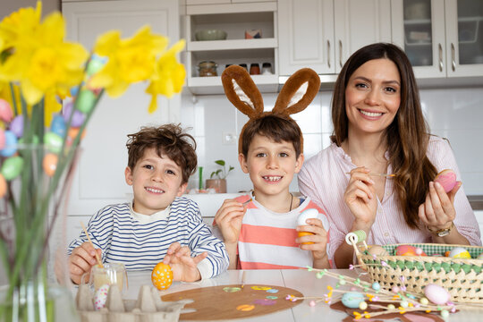 Mother and Two Sons Painting Easter Eggs at Home
