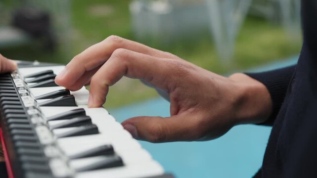 Man plays button melodica music instrument outside
